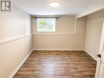 Barrie (Painswick North) apartment for rent - A spacious room with wooden flooring and a window.
