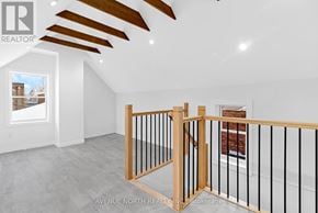Ottawa apartment for rent - A real estate brokerage logo is displayed on a wall in an empty room with a wooden staircase and a window showing a view of a building outside.