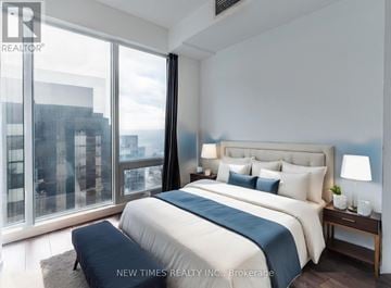 Toronto (Waterfront Communities) condo for rent - A bedroom with a large bed and a view of the city.