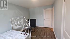 Toronto (Pleasant View) apartment for rent - A white metal bed frame with a quilted mattress sits in a room with light blue walls and a white door.
