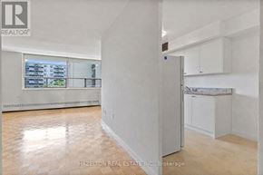 Toronto (Eglinton East) condo for rent - A spacious, empty room with a refrigerator and a window overlooking a building.