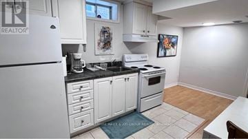 Richmond Hill (Rouge Woods) townhouse for rent - A kitchen with white cabinets and appliances, a fridge, a stove, and a dining table.