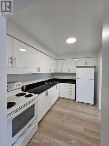 Aurora (Hills Of St Andrew) multi-family for rent - A white kitchen with a stove top oven and a refrigerator.