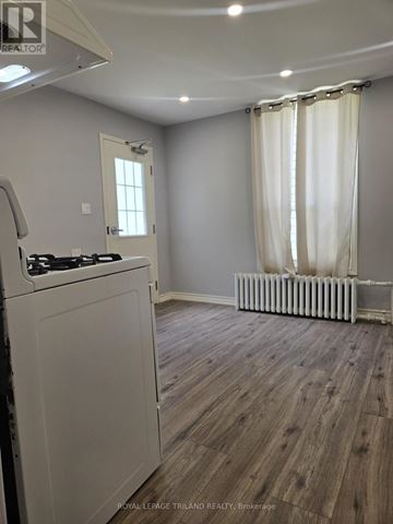 London North (North N) triplex for rent - A kitchen with a white stove top oven and a window with white curtains.