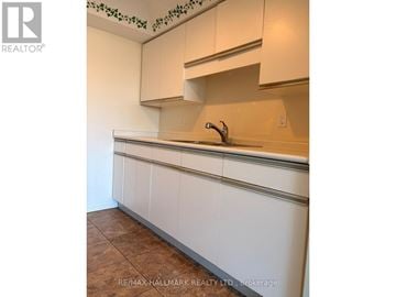 Guelph (Junction/Onward Willow) condo for rent - A kitchen with white cabinets and a brown floor.