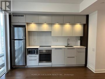 Toronto (Bay Street Corridor) condo for rent - A modern kitchen with white cabinets and stainless steel appliances.