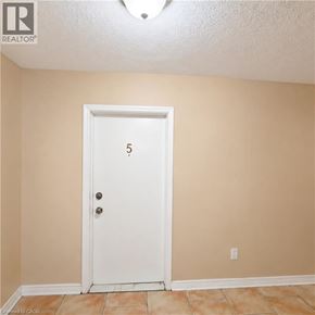 London apartment for rent - A white door with the number 5 on it in a room with tan walls.