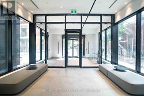 Toronto (North St. James Town) condo for rent - A hallway with glass doors and a green exit sign above them.