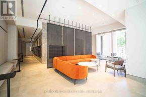 Toronto (North St. James Town) condo for rent - A modern living room with a large orange sofa and a glass partition wall.