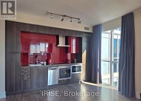 Toronto (Waterfront Communities) condo for rent - A modern kitchen with a red backsplash and stainless steel appliances.