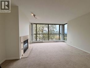 Burnaby apartment for rent - A spacious living room with a fireplace and large windows overlooking the water.