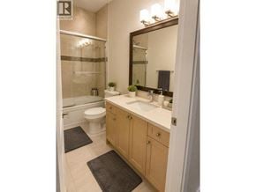 Coquitlam apartment for rent - A bathroom with a toilet, sink, and mirror.