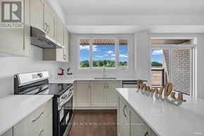 Oakville (Jm Joshua Meadows) townhouse for rent - A kitchen with white cabinets and a window with a view of trees.
