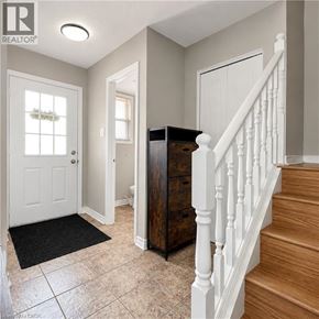 London apartment for rent - A hallway with a white door, a brown cabinet, and a staircase.