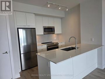 Mississauga (City Centre) condo for rent - A modern kitchen with white cabinets and stainless steel appliances.