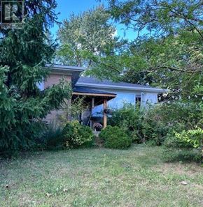 Halton Hills (Georgetown) apartment for rent - A house with a brown roof and a porch surrounded by greenery.