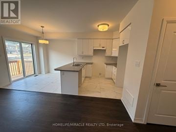 Brantford townhouse for rent - A kitchen area with white cabinets and a countertop is shown in the image.