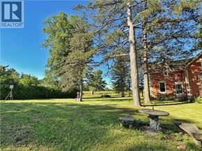 Waterford apartment for rent - A large tree stands in a yard with a picnic table and a bench.