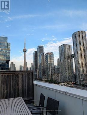 Toronto (Waterfront Communities) condo for rent - A cityscape with a wooden deck and chairs in the foreground.