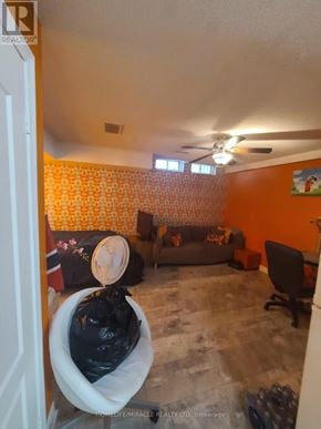 Pickering (Village East) house for rent - A living room with a grey couch and orange wallpaper.