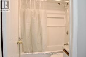 Woodstock (Woodstock - North) condo for rent - A white bathroom with a shower curtain and a toilet.