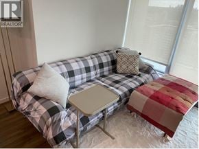 Burnaby apartment for rent - A grey and white checkered couch with a white pillow and a small white table in front of it.