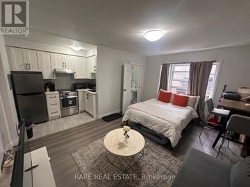 Toronto (Casa Loma) multi-family for rent - A bedroom with a bed, a table, and a kitchen area.