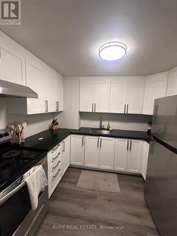 Toronto (Kensington-Chinatown) multi-family for rent - A kitchen with white cabinets and black countertops.