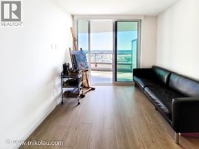 Vancouver apartment for rent - A living room with a black couch and a wooden floor.