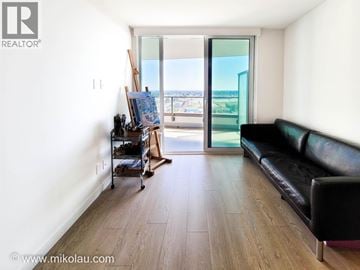 Vancouver apartment for rent - A living room with a black couch and a wooden floor.