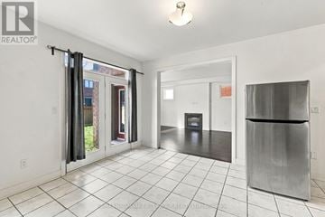 Whitby apartment for rent - A white tiled kitchen with a refrigerator and a door leading outside.