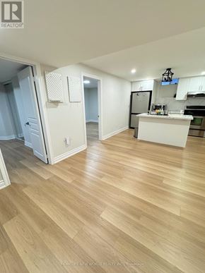 Markham (Box Grove) apartment for rent - A room with wooden flooring and a kitchen area in the background.