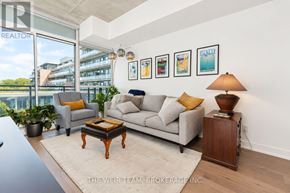 Toronto (South Riverdale) condo for rent - A living room with a grey couch, a coffee table, and a lamp on a side table.