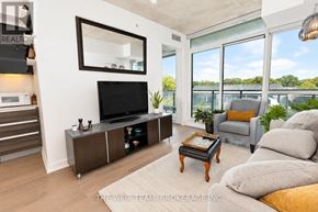 Toronto (South Riverdale) condo for rent - A living room with a grey couch, a black television, and a large window.
