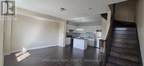 Milton (Ha Harrison) townhouse for rent - A spacious living room with a kitchen in the background and a staircase on the right.