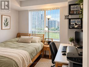 Richmond Hill (Langstaff) condo for rent - A bedroom with a bed, desk, and window with a view of a city.