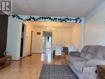 Toronto (Tam O'shanter-Sullivan) apartment for rent - A living room with a grey couch, a dining table with chairs, and a chandelier.
