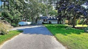 Orillia apartment for rent - A house with a driveway surrounded by trees and bushes.
