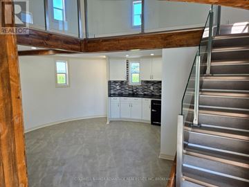 Niagara Falls (Schisler) apartment for rent - A large open space with a staircase on the right and a kitchen area with a countertop and cabinets on the left.