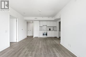 Toronto (Thorncliffe Park) condo for rent - A spacious kitchen with white cabinets and a wooden floor.