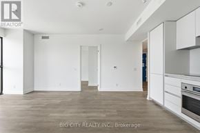 Toronto (Thorncliffe Park) condo for rent - A spacious, empty room with a kitchen area to the right.