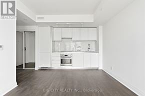 Toronto (Thorncliffe Park) condo for rent - A white kitchen with a white fridge, white cabinets, and a white oven.