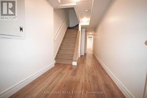 Burlington (Shoreacres) townhouse for rent - A hallway with a staircase and a sign that says "Kingsway Real Estate Brokerage".