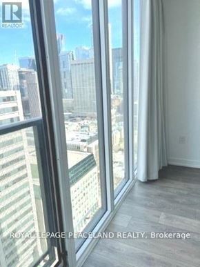 Toronto (Kensington-Chinatown) condo for rent - A room with a view of the cityscape through large windows.