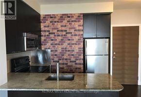 Toronto (Willowdale East) condo for rent - A kitchen with a brick wall and a refrigerator.