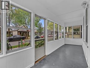 Windsor apartment for rent - A sunny day in a neighborhood with houses and cars visible through the windows of a building.