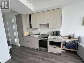 Mississauga (City Centre) condo for rent - A modern kitchen with wooden cabinets and stainless steel appliances.