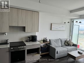 Mississauga (City Centre) condo for rent - A modern kitchen with a stove top oven and a grey couch.