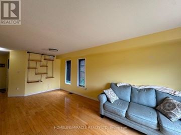 Orangeville apartment for rent - A living room with a grey couch and wooden floors.