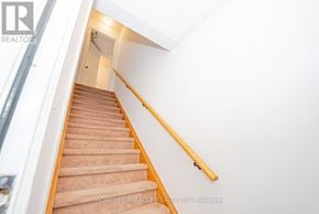 Oakville (Ro River Oaks) townhouse for rent - A staircase with a wooden handrail and beige carpeted steps.